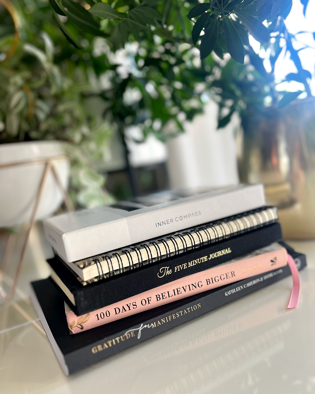 A stack of books sit on a desk