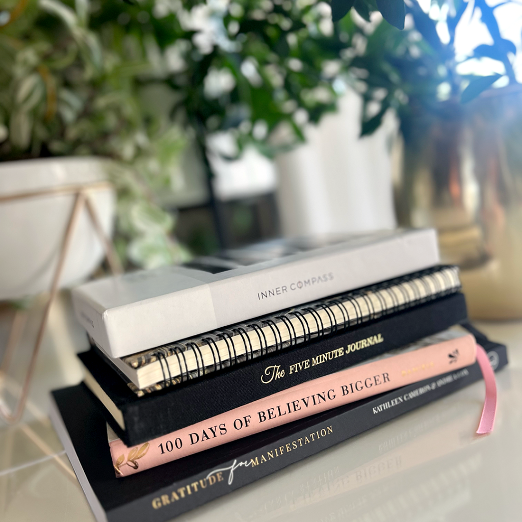 A stack of books sit on a desk